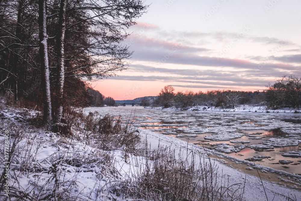 Frozen river with ice flow. Purple sunset.