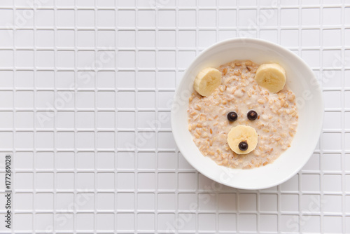 oatmeal porridge with fruit and berries. children's food with a bear face