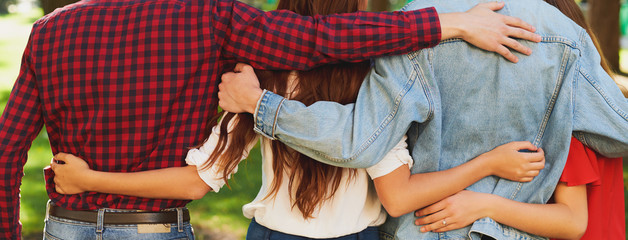 Best friends forever. Group of happy young unrecognizable man and woman hugging together and talking on city street from back. Happiness, leisure, friendship, teamwork, family travels concept