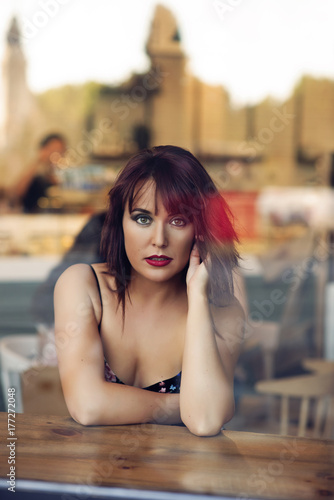 beauty redhead girl behind a glass sitting in a coffee shop