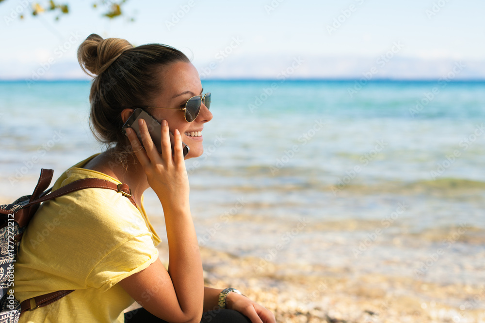 Beautiful young woman talking on phone on the beach