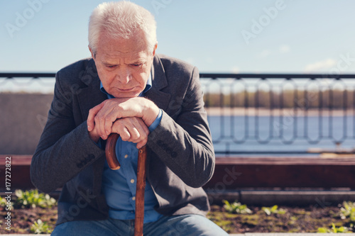 Upset senior man pondering while sitting on bench