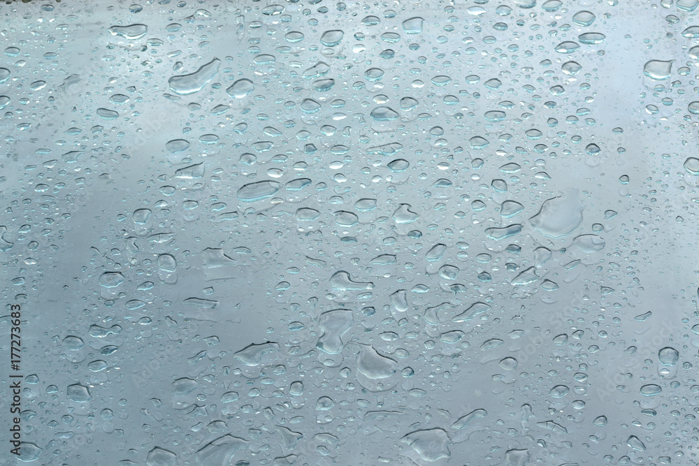 Rain drops on a blue glass forming a water textured background. Empty copy space for Editor's content. Rain drops on a blue glass forming a water textured background. Empty copy space for Editor's content.