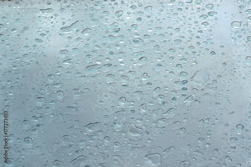 Rain drops on a blue glass forming a water textured background. Empty copy space for Editor's content.