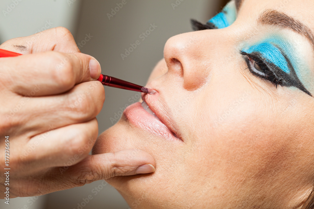Makeup artist applying lipstick to a white woman
