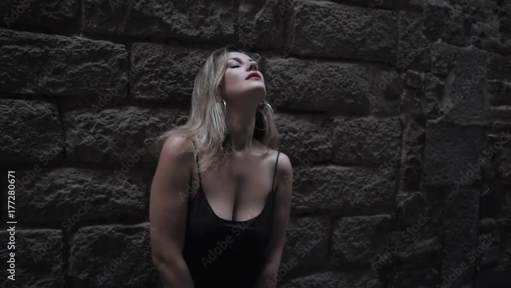 Portrait of seduction elegant woman standing in the old european city wall. Attractive lady in long sexy black dress in gothic quarter of Barcelona. inviting girl touching her body. Slow motion. Portrait of seduction elegant woman standing in the old european city wall. Attractive lady in long sexy black dress in gothic quarter of Barcelona. inviting girl touching her body. Slow motion.