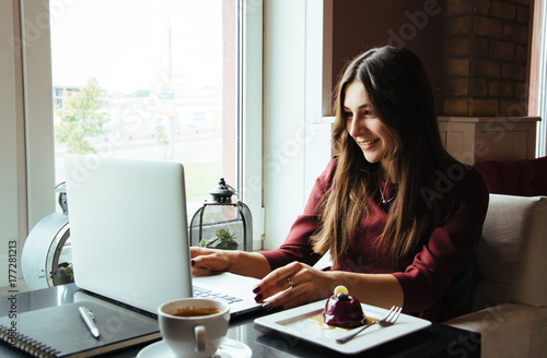 Young attractive woman sitting in a cafe in the morning before her work and planning tasks for the whole day. Beautiful lady talking on the phone and discussing business strategies with her colleague.