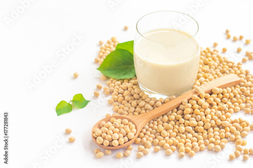 A glass of soy milk with soybeans on wooden spoon isolated on white background. 