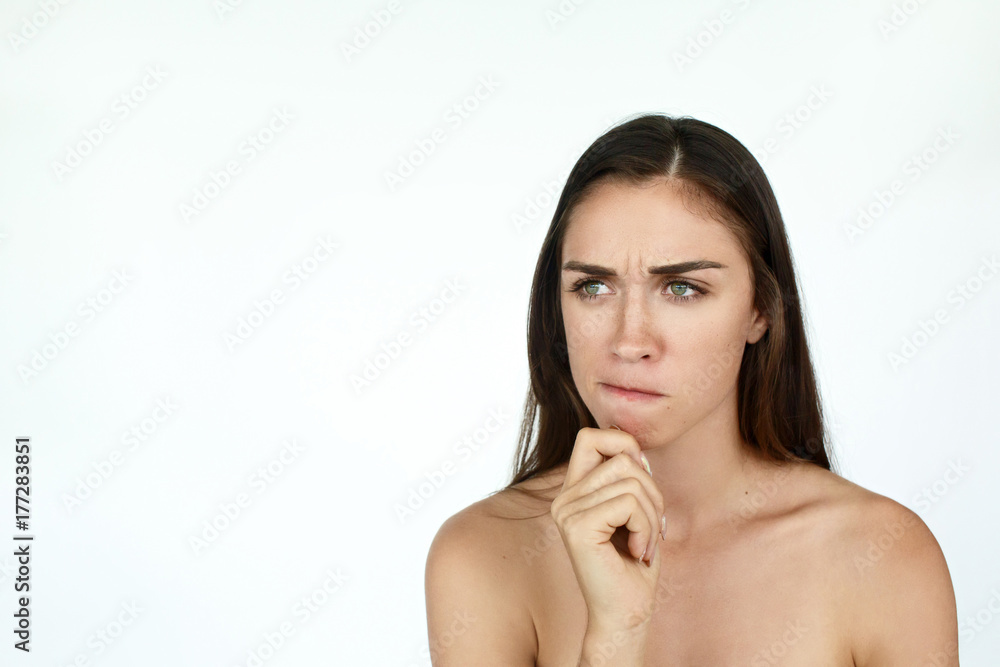 Thoughtful young woman holds fingers on her chin standing on white background Thoughtful young woman holds fingers on her chin standing on white background