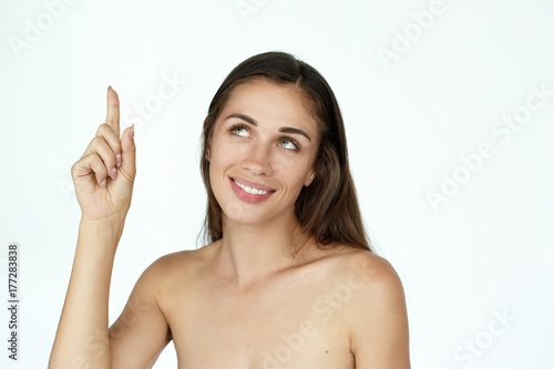 Happy young woman raises her finger up standing on white background