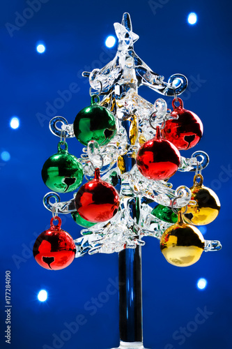 Glass christmas tree with colorful balls on blurred lights background