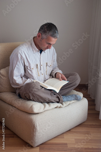 a man on an armchair reads a book