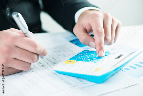 Businessman sitting at the desk, calculating sales earnings