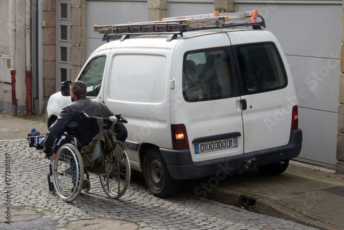 Personne en fauteuil roulant obligée de passer sur la route à cause d'une voiture mal garée  photo