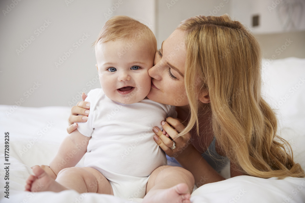 Mother Lying On Bed At Home Gives Baby Son Kiss Mother Lying On Bed At Home Gives Baby Son Kiss
