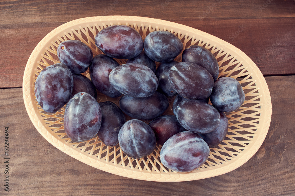 Fototapeta premium plum in a wicker basket on the wooden table