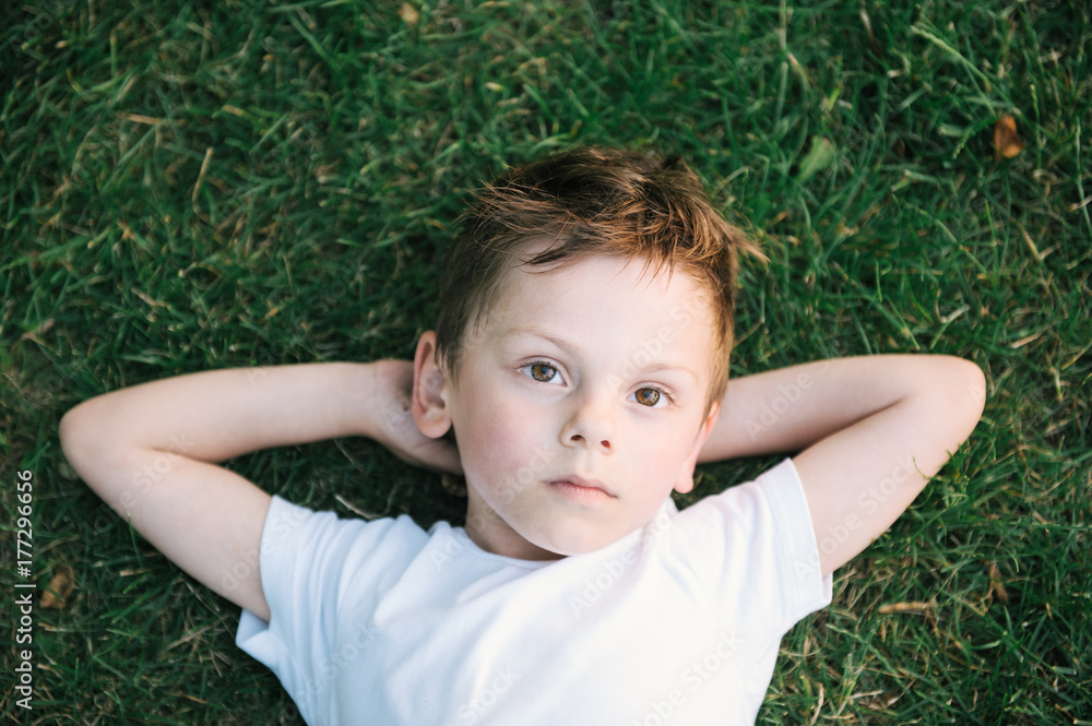 beautiful pensive kid lying on green grass beautiful pensive kid lying on green grass