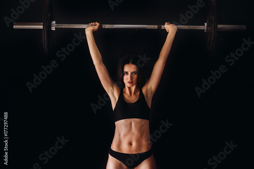 Woman holds up a barbell doing intense workout