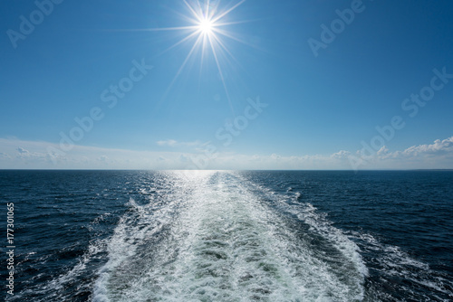 Sun shining over the wake of cruise ship at sea