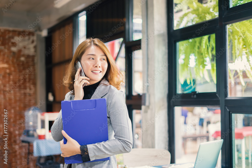 Smiling Business woman working in office with documents,Happy Asian businesswoman using phone sitting on chair at modern home studio.Concept of young people working mobile devices,contact to costumer Smiling Business woman working in office with documents,Happy Asian businesswoman using phone sitting on chair at modern home studio.Concept of young people working mobile devices,contact to costumer