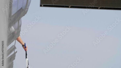 Man holding and waving Checkered race flag in slow motion at finish line on a raceway. Victory, achievement, success and sport concept.
