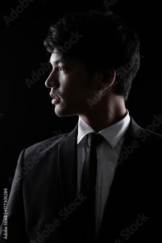 Asian man in black fomal suit in the dark