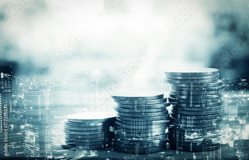 Double exposure of city and stack of coins for finance and banking concept