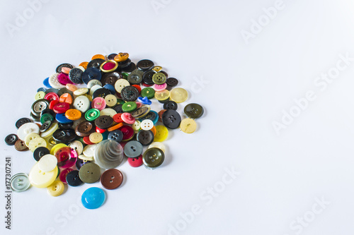 Many different buttons. Buttons for clothes made of plastic. Buttons are scattered on a light background. Many buttons. photo