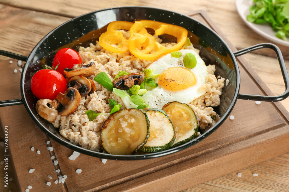 Frying egg with oatmeal, egg, mushrooms and vegetables on table Frying egg with oatmeal, egg, mushrooms and vegetables on table