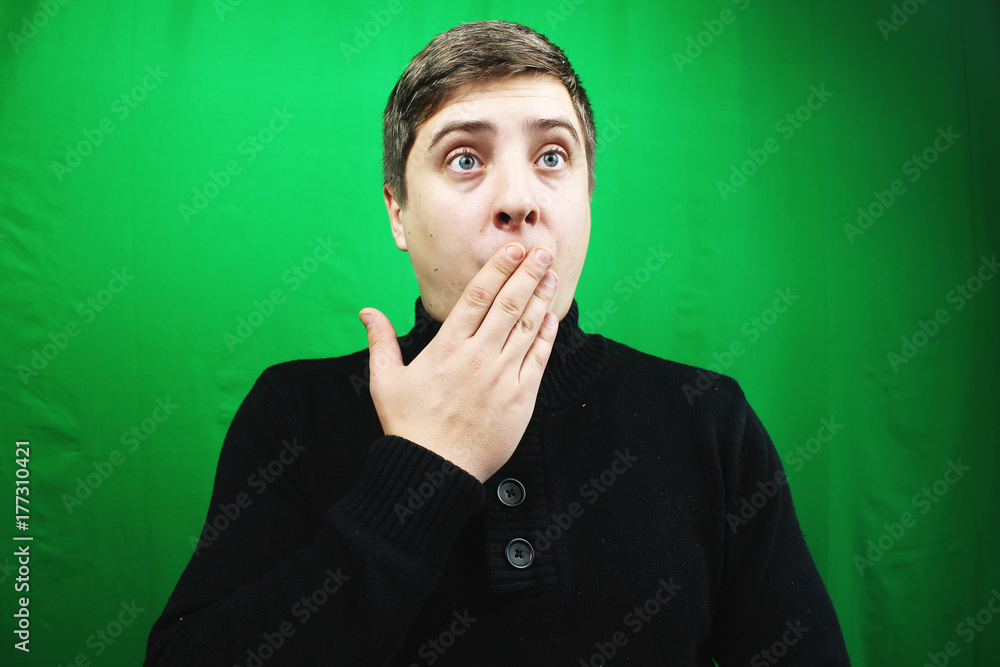 Surprised handsome man showing something. Green background Surprised handsome man showing something. Green background