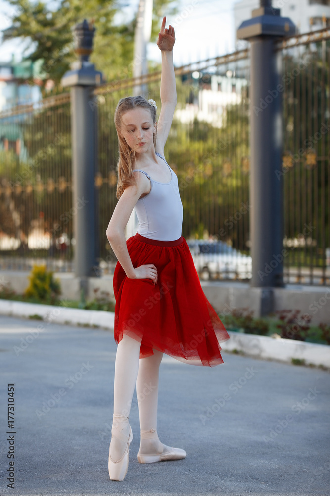 Young beautiful ballerina dancing outdoors in a park. Full length portrait.