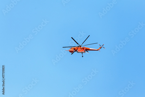 Red firefighter Helicopter flying fast in the blue sky during the emergency call in the city