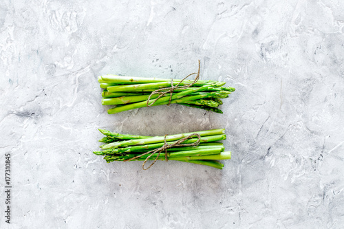 Bunches of fresh asparagus sprouts on grey stone background top view