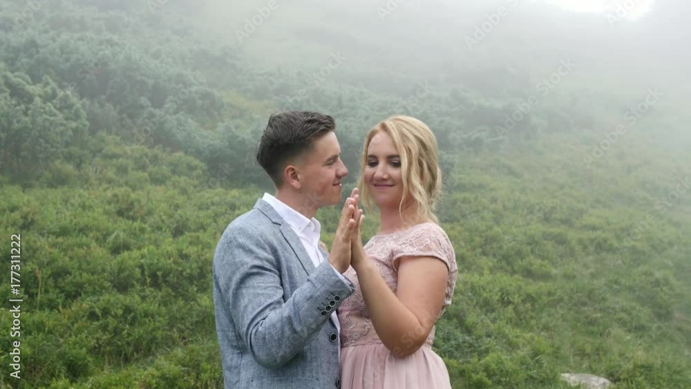 Luxury couple in evening dresses are hugging on the mountain meadow Luxury couple in evening dresses are hugging on the mountain meadow