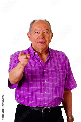 Portrait of a happy old man, pointing with his hand to somewhere wearing a purple square t-shirt in a white background