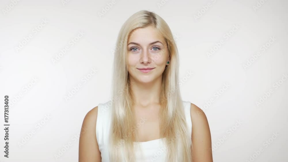cute young blond blue-eyed girl looking at camera smiling over white background. Concept of emotions cute young blond blue-eyed girl looking at camera smiling over white background. Concept of emotions