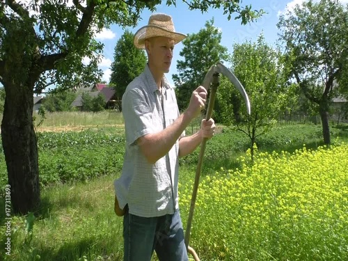 The man is sharpening a blade of a spit for easy mowing.