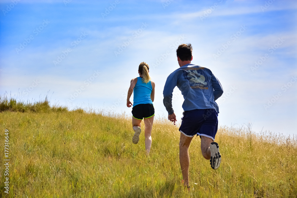 couple running up a hill side in Colorado couple running up a hill side in Colorado