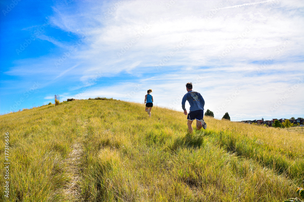 couple running up a hill side in Colorado
