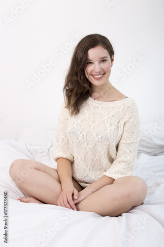 Happy young woman sitting on her bed