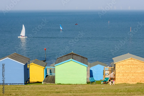 Colourful beach hits at the bottom of the grass area  in Tankerton, known as the slopes. The windfarm can be seen on the horizon photo