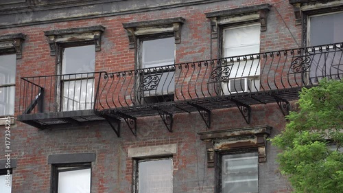 Exterior day establishing shot of a Brooklyn style apartment building in New York City. Windows sit over the fire escape on a brick facade