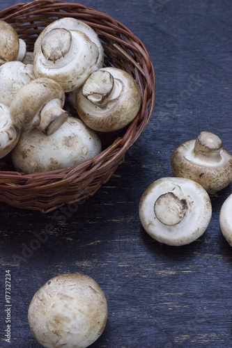 fresh mushrooms in a basket on the wooden table.