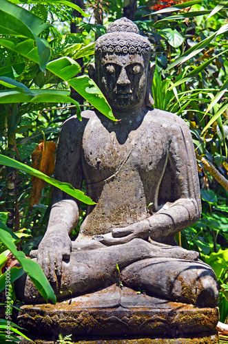 An ancient statue of an abandoned Buddha in the thickets of the equatorial jungle.