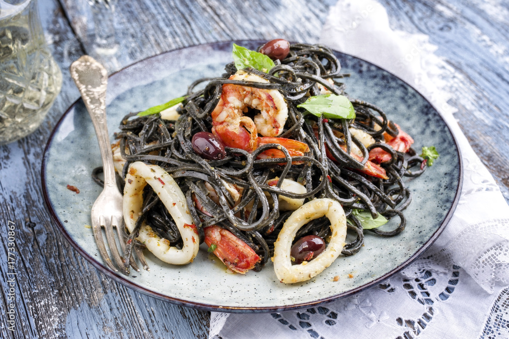 Italian linguine con tinta de calamari and prawns with olives as close-up  on a plate Stock Photo | Adobe Stock