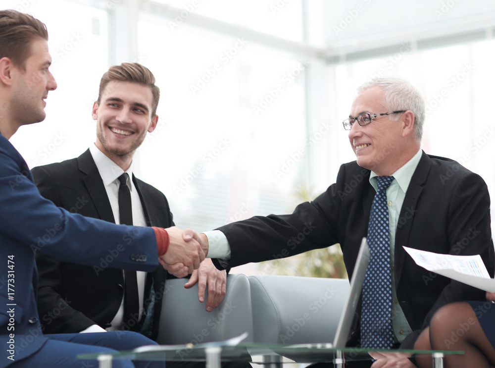 Partners concluding deal and shaking hands in the presence of team members Partners concluding deal and shaking hands in the presence of team members