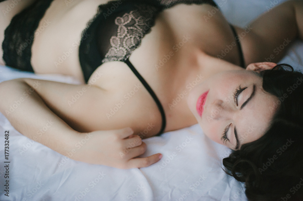 Woman in black lace bra lying on bed Stock Photo