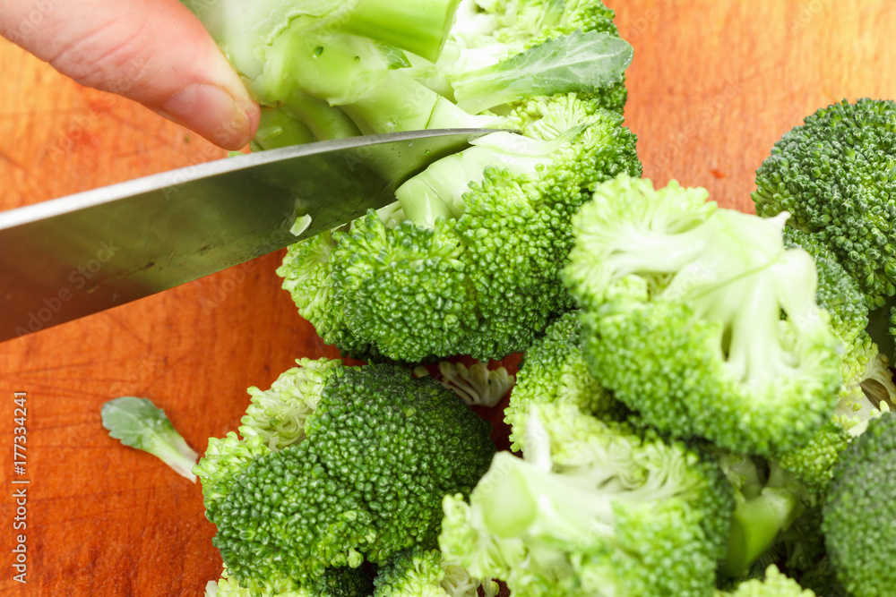 Chef cutting fresh green broccoli for cooking. Stock up on winter food.