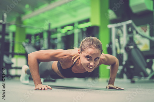 The happy sportswoman doing push up exercise in the gym