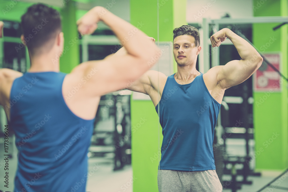 Fototapeta premium The sportsman pose in front of the mirror in the gym